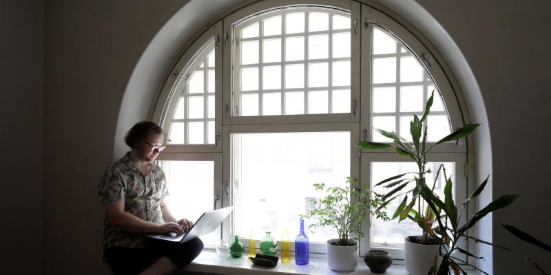 Haastatelta Severi Hämäri istuu tietokoneen kanssa työhuoneensa ikkunalaudalla.