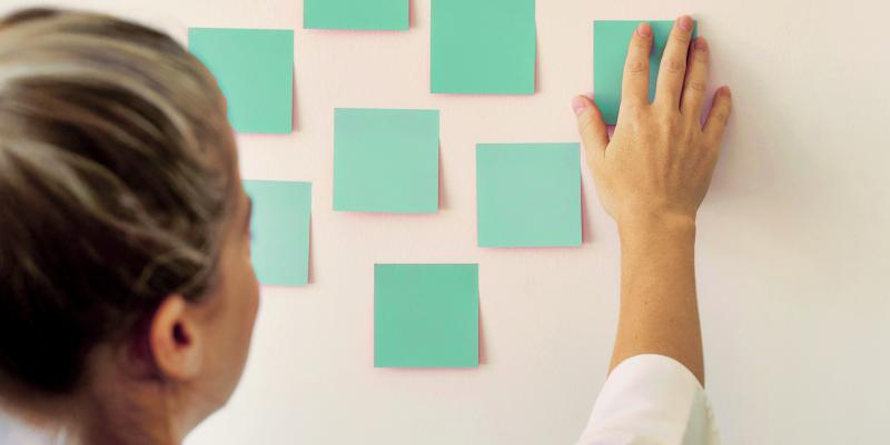 Kuvituskuva jossa vihreitä tyhjiä post-it lappuja seinällä
