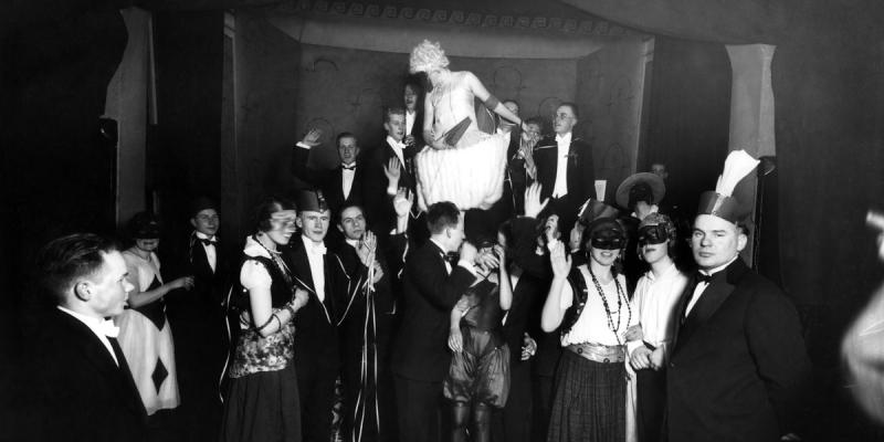 Svartvit bild på festfolk i maskeraddräkter, 1920-tal.